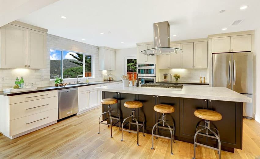 Contemporary kitchen with white cabinetry, dark color island, gray quartz and white marble counters and light wood flooring